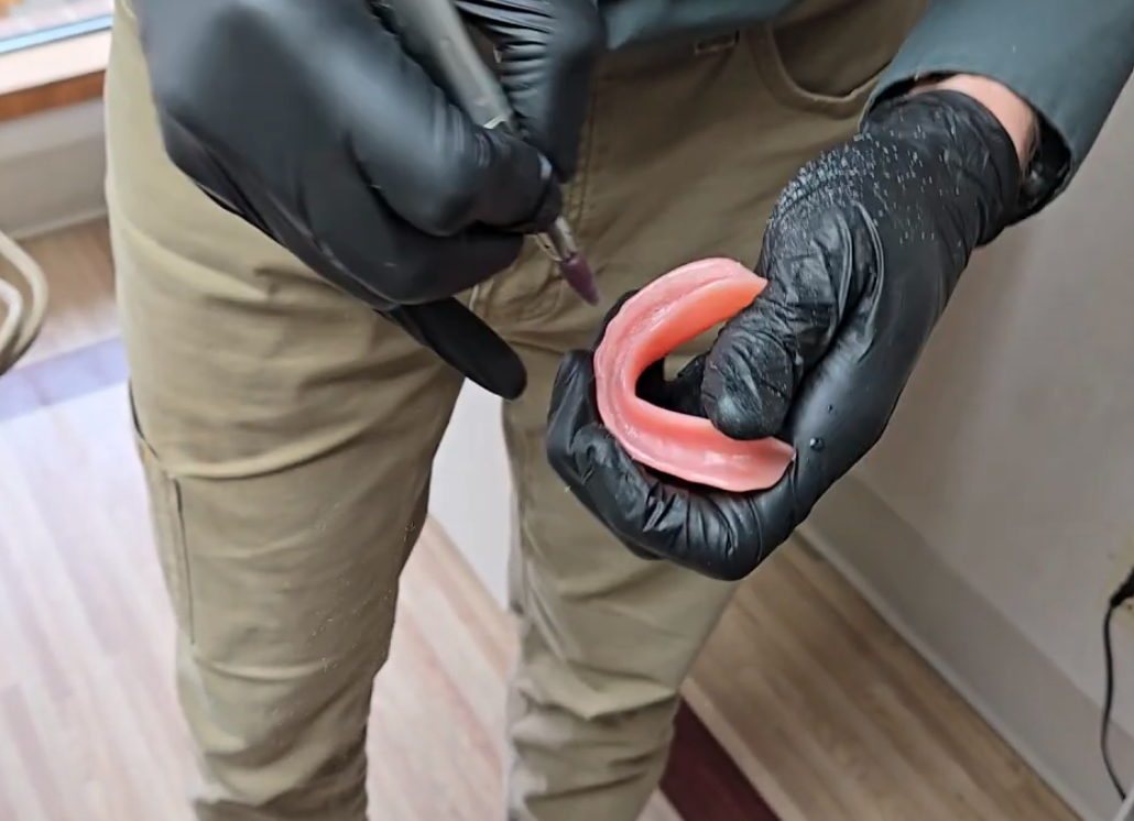 Dr. Jonny Fisher shaping a denture with a dental handpiece to relieve a pressure point